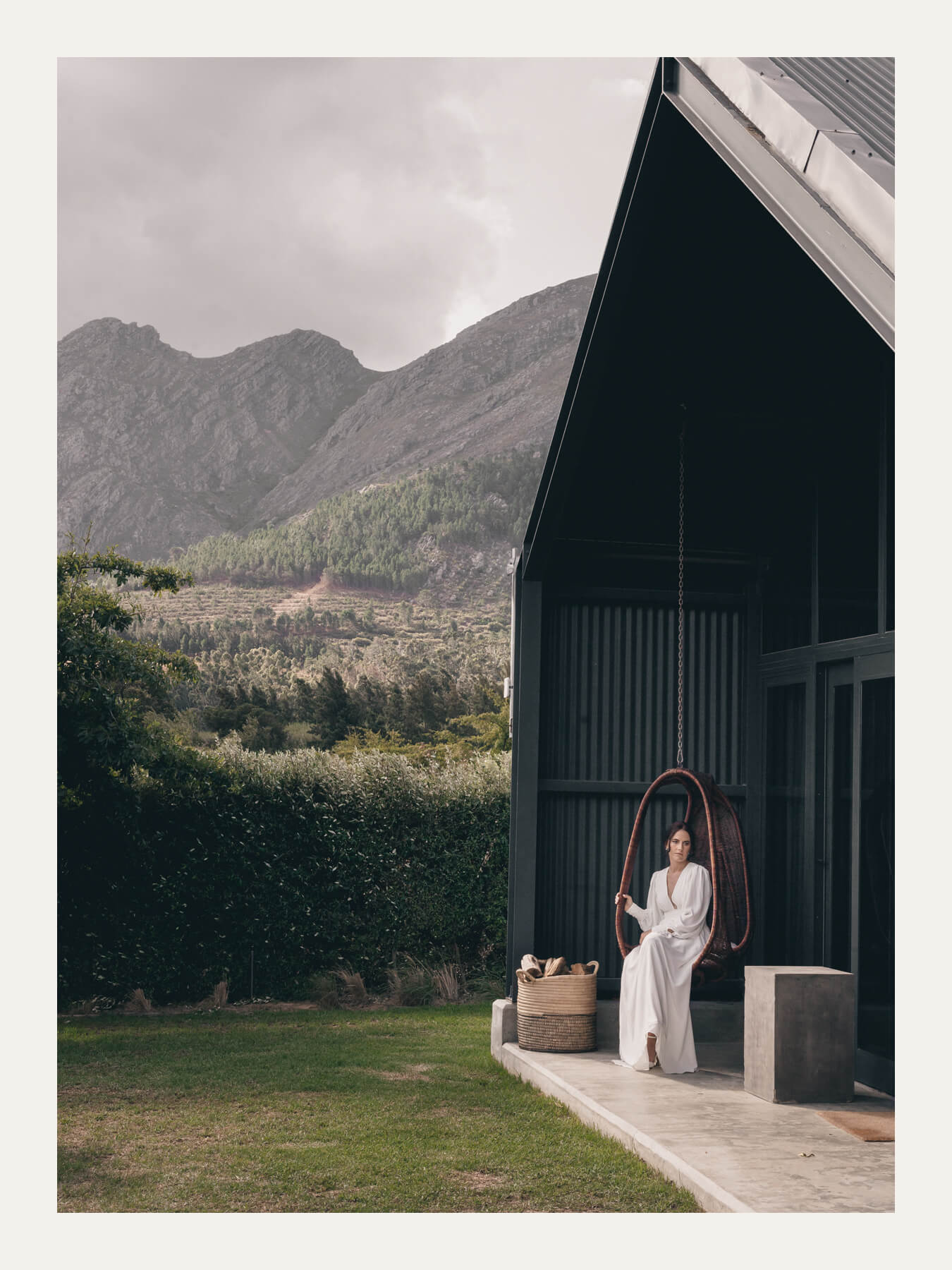 Bride in a doorway of a dark modern barn below the mountains. Ben Viljoen Photography
