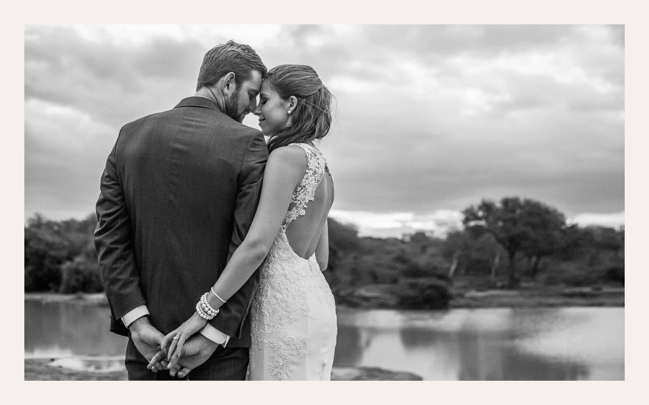 Couple holding hands with their backs turned, looking over a waterhole in the bush. Ben Viljoen Photography