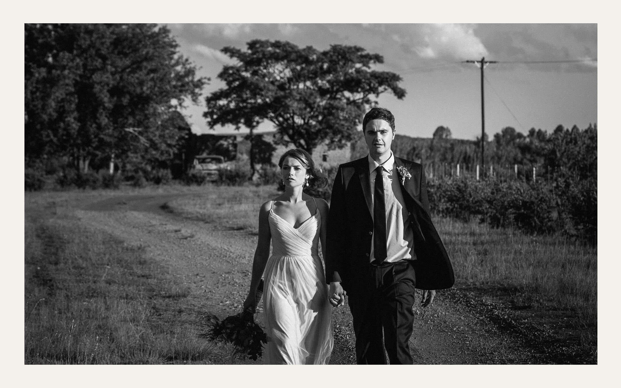 Bride and groom walking a farm track past an old homestead. Ben Viljoen Photography